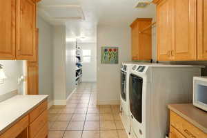 Laundry room featuring cabinet space, light tile patterned floors, and independent washer and dryer