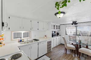 Kitchen featuring light countertops, white cabinetry, a textured ceiling, and white appliances