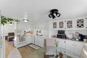 Kitchen with light countertops, white cabinetry, white appliances, light wood-style floors, and a textured ceiling