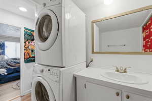 Laundry room featuring stacked washer / drying machine and wood finished floors