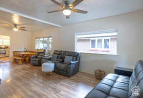 Living area with dark wood-style flooring, healthy amount of natural light, and a ceiling fan