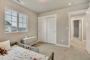 Bedroom with light colored carpet and a closet
