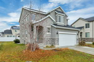 Traditional home with stone siding, stucco siding, and driveway