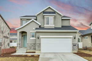 Traditional-style house featuring stone siding, stucco siding, driveway, and a shingled roof