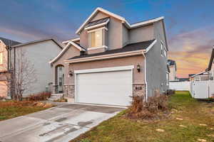 View of front of house with stone siding, stucco siding, concrete driveway, and a garage