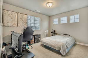 Bedroom featuring a textured ceiling, an office area, and carpet