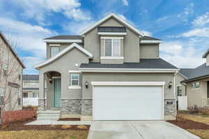 Traditional-style house with stone siding, stucco siding, concrete driveway, and a garage