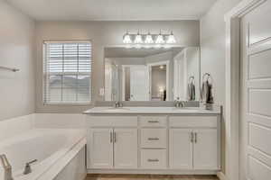 Bathroom with double vanity, a garden tub, and a stall shower