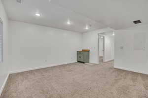 Empty room featuring light carpet, electric panel, and recessed lighting