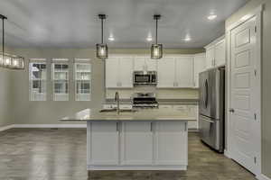 Kitchen featuring stainless steel appliances, light wood-style flooring, white cabinetry, light stone counters, and decorative backsplash