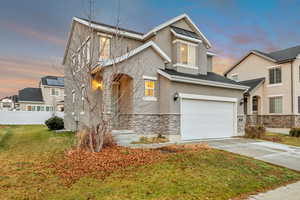 Traditional home with stone siding, concrete driveway, stucco siding, and a standing seam roof