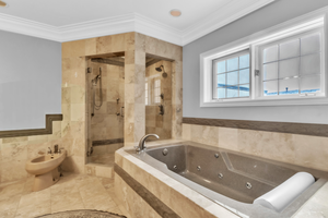 Full bathroom with a jetted tub, a shower stall, a bidet, crown molding, and tile walls