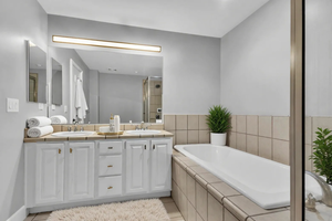 Bathroom featuring double vanity, a garden tub, a stall shower, and light tile patterned floors