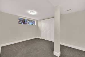 Unfurnished bedroom with dark carpet and a closet