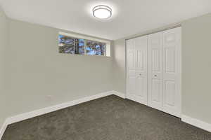 Unfurnished bedroom with dark carpet and a closet