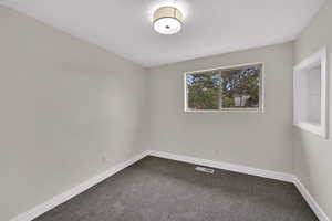 Empty room featuring dark carpet and baseboards