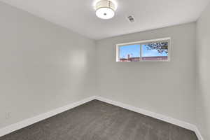 Unfurnished room with baseboards and dark carpet