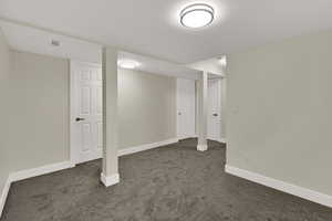 Finished below grade area featuring dark carpet and baseboards