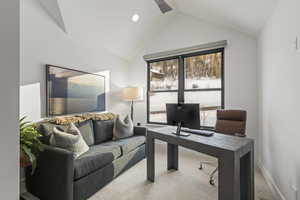 Home office with light carpet and vaulted ceiling