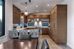Kitchen featuring open shelves, vaulted ceiling, high end stove, decorative light fixtures, and modern cabinets