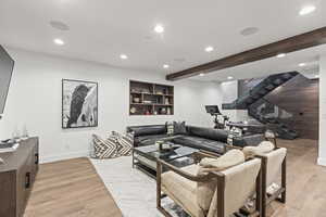 Living area featuring stairway, light wood finished floors, recessed lighting, and beamed ceiling