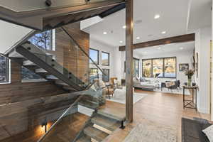 Stairway with wood finished floors, beamed ceiling, and recessed lighting