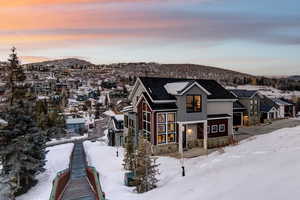 Snow covered rear of property with stone siding, a residential view, and a mountain view
