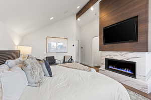 Bedroom with beam ceiling, a high end fireplace, high vaulted ceiling, wood finished floors, and recessed lighting