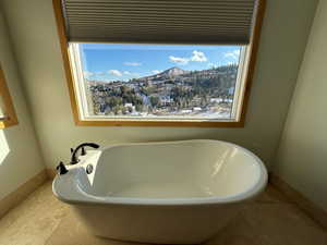 Bathroom with a freestanding tub, a mountain view, and tile patterned floors