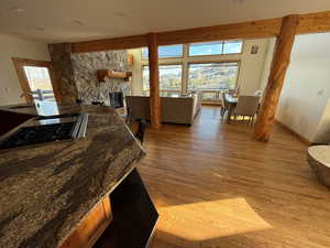 Kitchen with dark stone counters, light wood-style flooring, a stone fireplace, open floor plan, and a breakfast bar