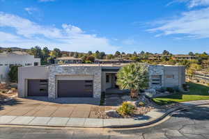 Contemporary home featuring a garage, concrete driveway, stucco siding, and stone siding