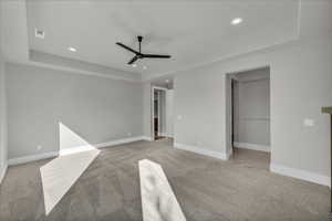 Unfurnished room featuring a tray ceiling, recessed lighting, light carpet, and ceiling fan