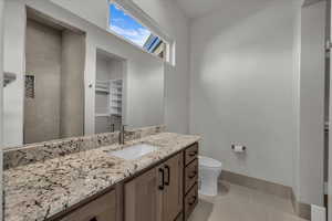 Bathroom with a spacious closet, vanity, and light tile patterned floors