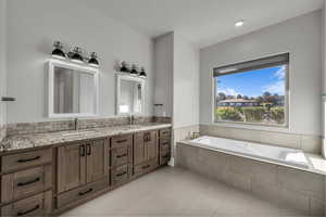 Full bathroom with double vanity, a garden tub, tasteful backsplash, and light tile patterned floors