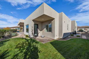 Rear view of property featuring stucco siding, a patio, and a yard