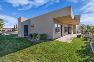 Rear view of property featuring stucco siding, a patio area, and a yard
