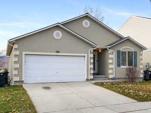 View of front of property with stucco siding, a front yard, concrete driveway, and a garage