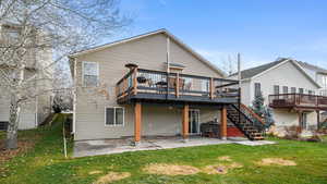 Back of property featuring a lawn, a deck, a patio area, and stairs