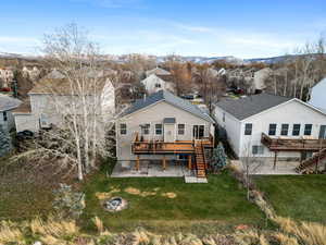 Back of property with stairway, a fire pit, a wooden deck, a lawn, and a residential view