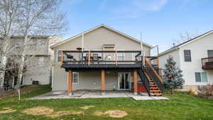 Rear view of house with a lawn, a patio, a wooden deck, and stairs