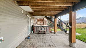 View of patio with stairway, a hot tub, and a mountain view