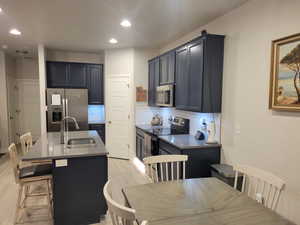 Kitchen with appliances with stainless steel finishes, an island with sink, backsplash, a kitchen breakfast bar, and recessed lighting