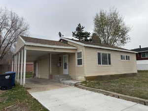 View of front of house featuring driveway, a carport, a porch, and roof with shingles