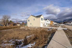 View of side of home with an attached garage, driveway, and a residential view