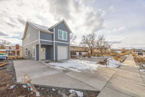View of snowy exterior featuring driveway and a garage