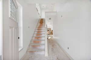 Stairway featuring a high ceiling and unfinished concrete flooring