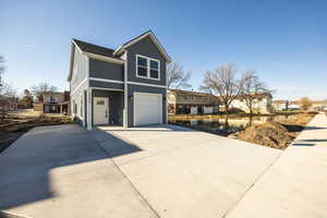 View of front of house featuring concrete driveway, an attached garage, and a residential view