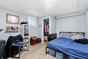 Bedroom featuring a walk in closet, wood finished floors, and an office area