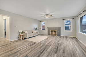 Living room with light wood finished floors, a fireplace, and ceiling fan