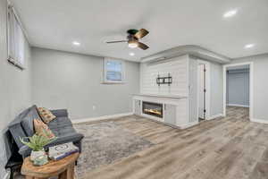 Sitting room featuring a glass covered fireplace, light wood-style floors, ceiling fan, and recessed lighting